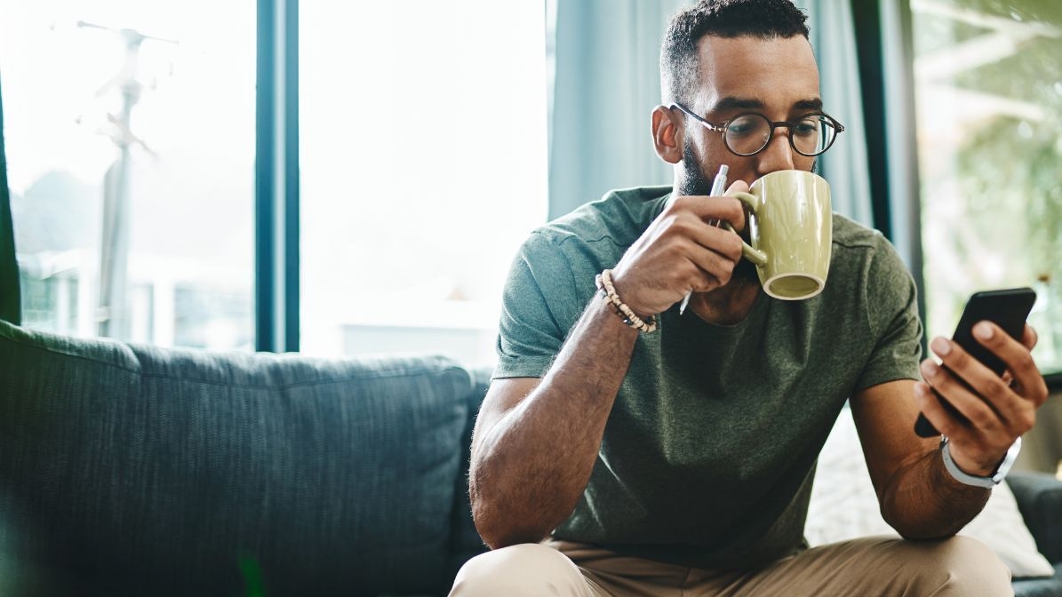 man drinking coffe checking phone